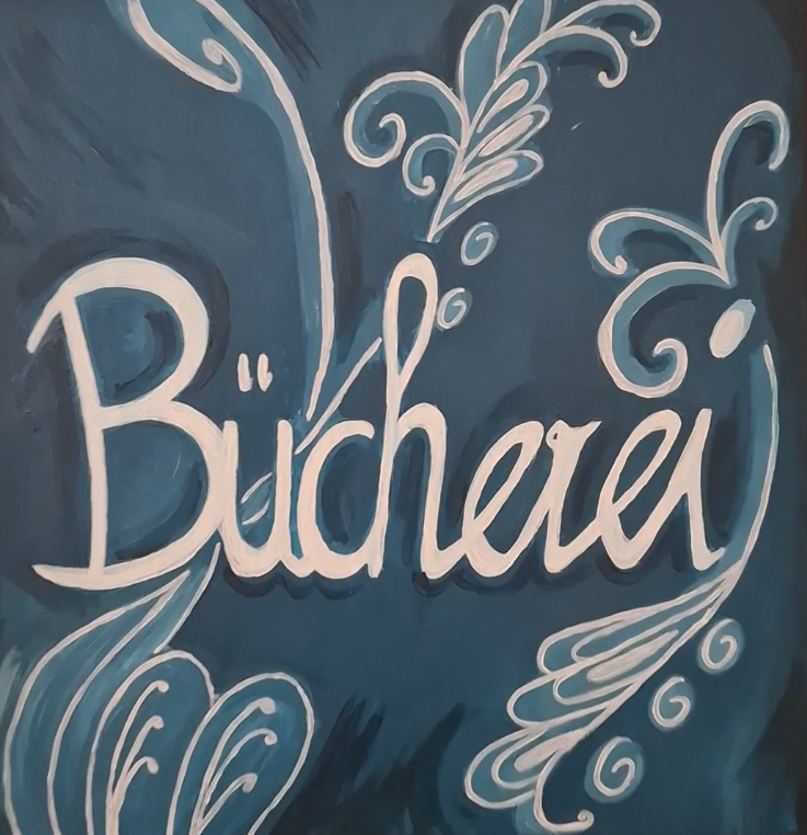Handgemaltes Schild „Bücherei“ in Weiß auf blauem Hintergrund mit verzierten Schnörkeln